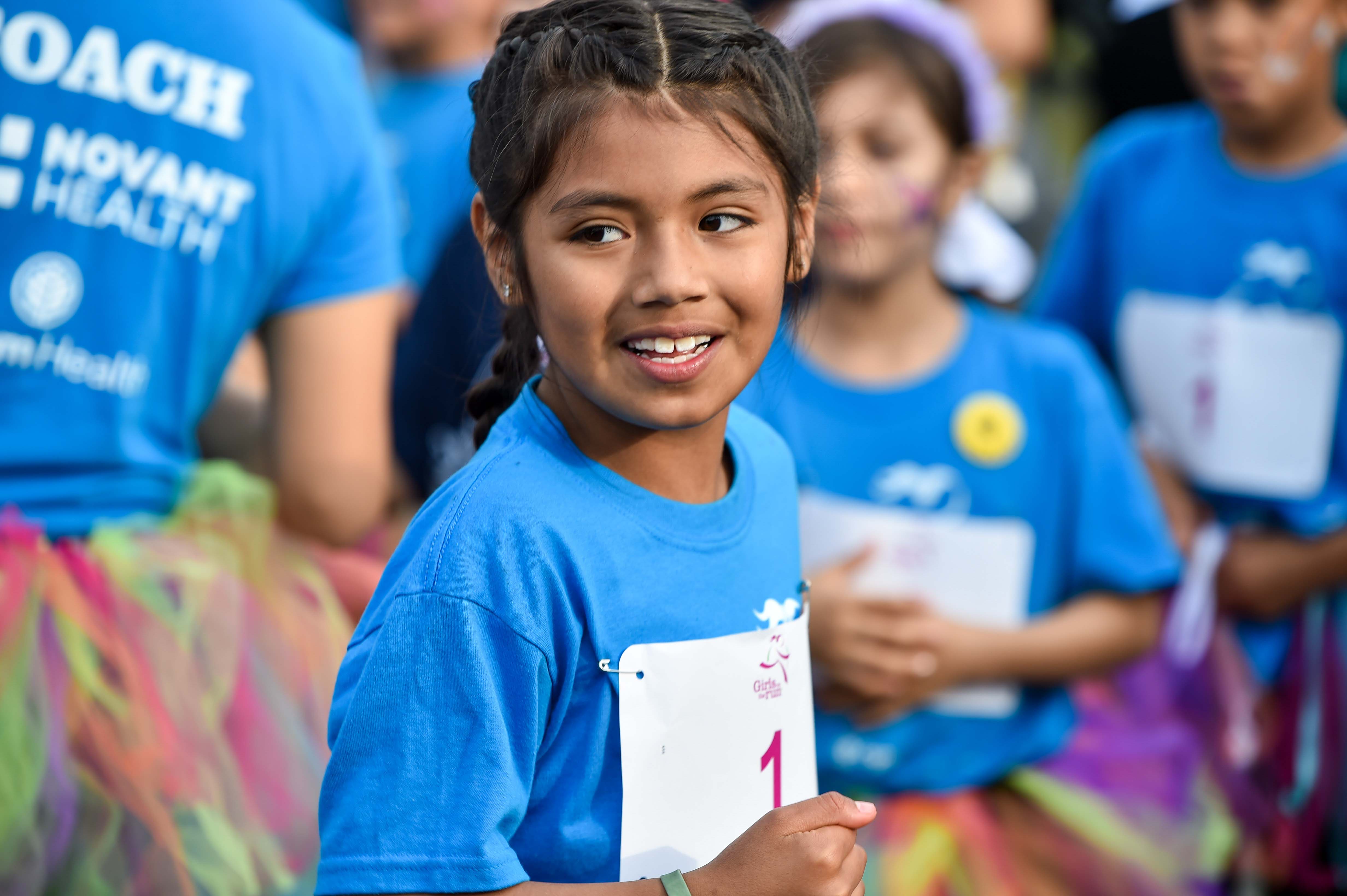 Girls on the Run participant high fives running buddy at 5K  